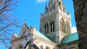 En historisk kyrka med ett högt torn, stora, välvda fönster och en fasad av sten.