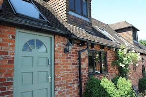 A brick house with a green door, a window with a black frame, and a chimney.