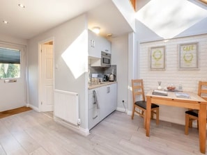 A modern kitchen with a dining area, white cabinetry, and a wooden table.