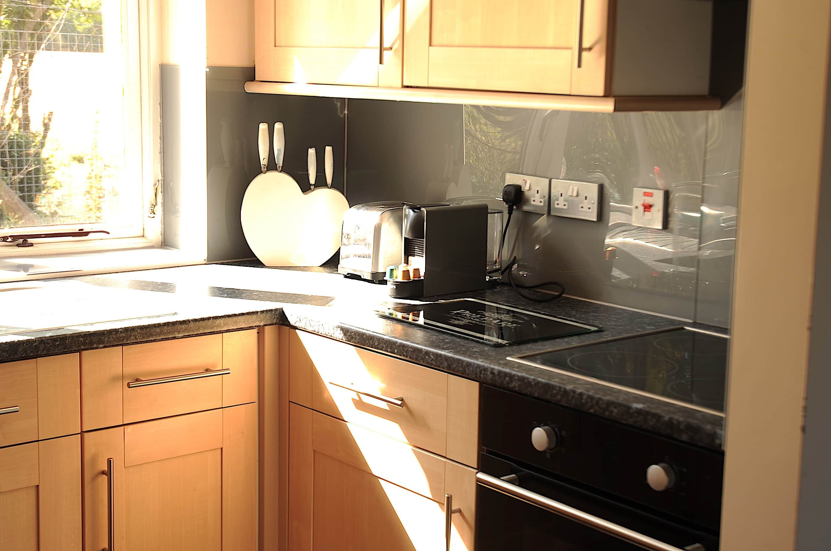 A kitchen with wooden cabinets, a built-in oven, a toaster, and a window providing natural light.