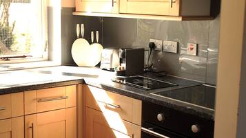 A kitchen with wooden cabinets, a built-in oven, a toaster, and a window providing natural light.