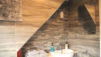 A bathroom with a dual sink, a mirror, and a towel rack.