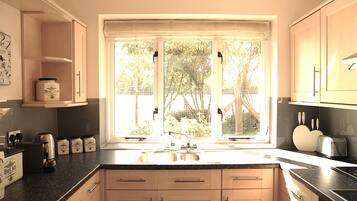 A kitchen with a large window, wooden cabinets, and a countertop with various appliances and jars.