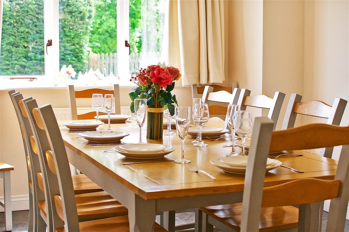 A dining table set with plates, glasses, and a vase of flowers.