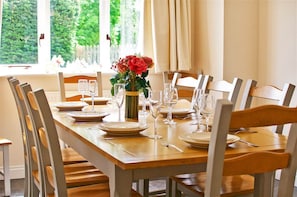 A dining table set with plates, glasses, and a vase of flowers.
