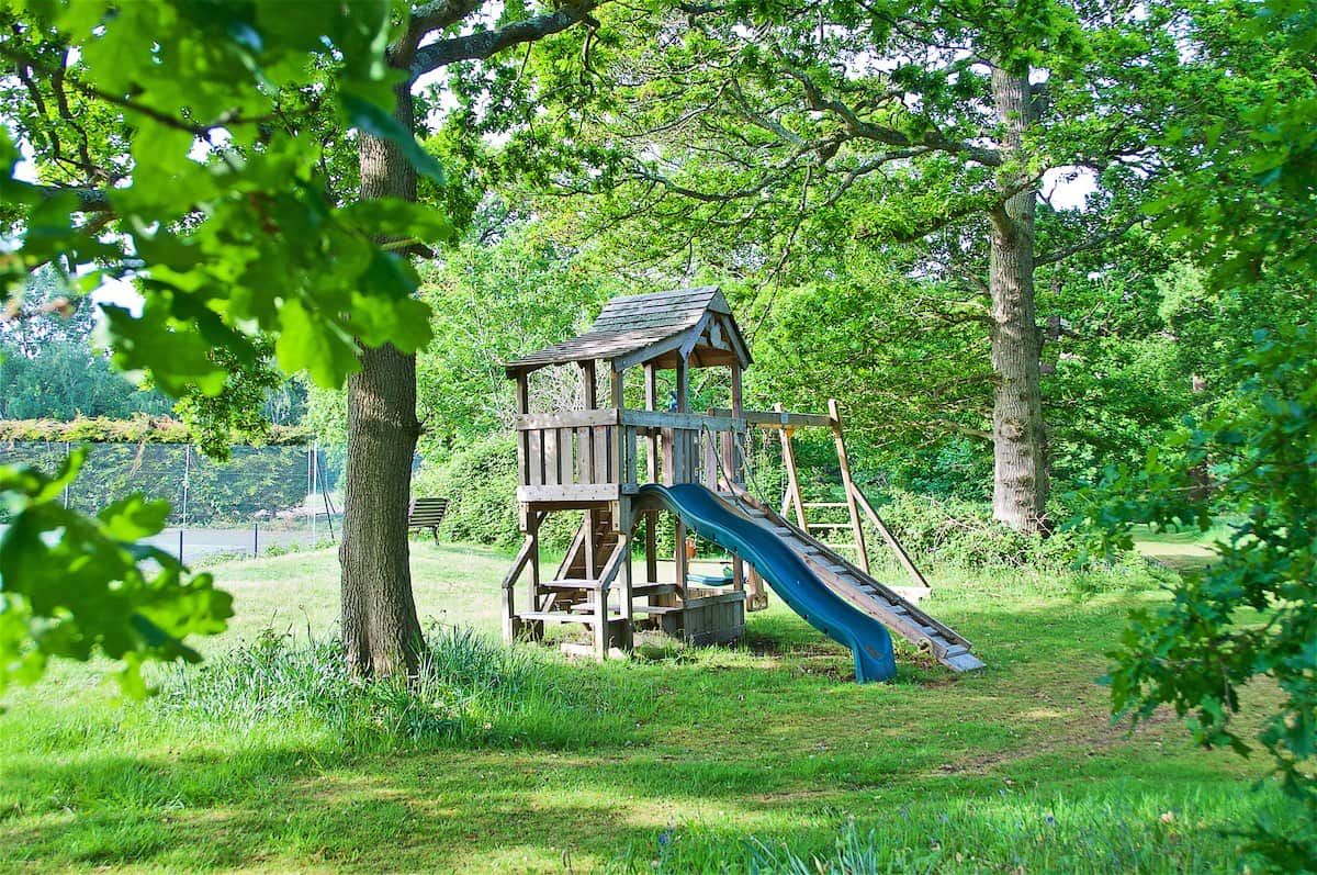 A wooden play structure with a slide in a grassy park area.