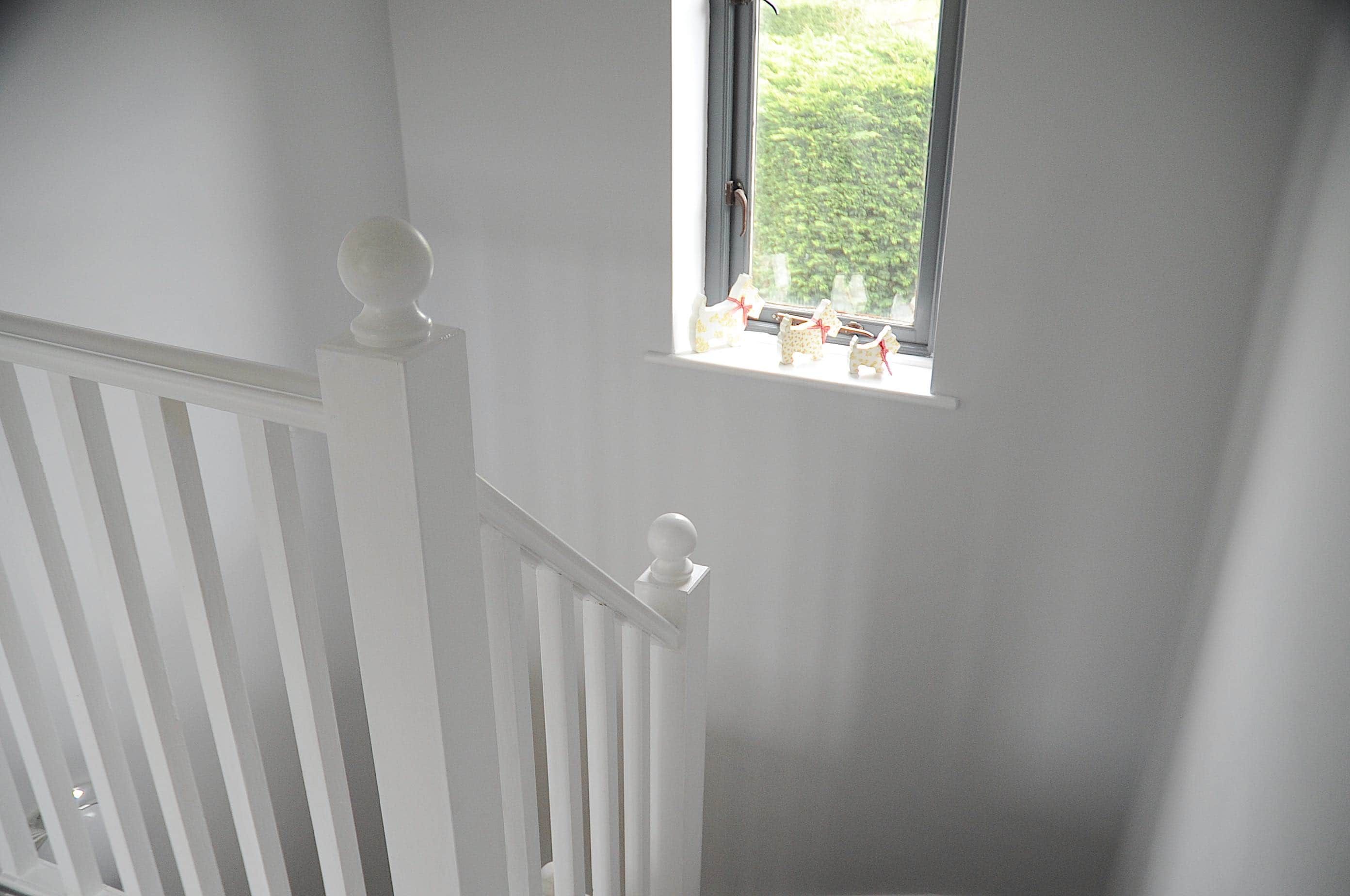 Un escalier blanc avec une petite fenêtre en haut.