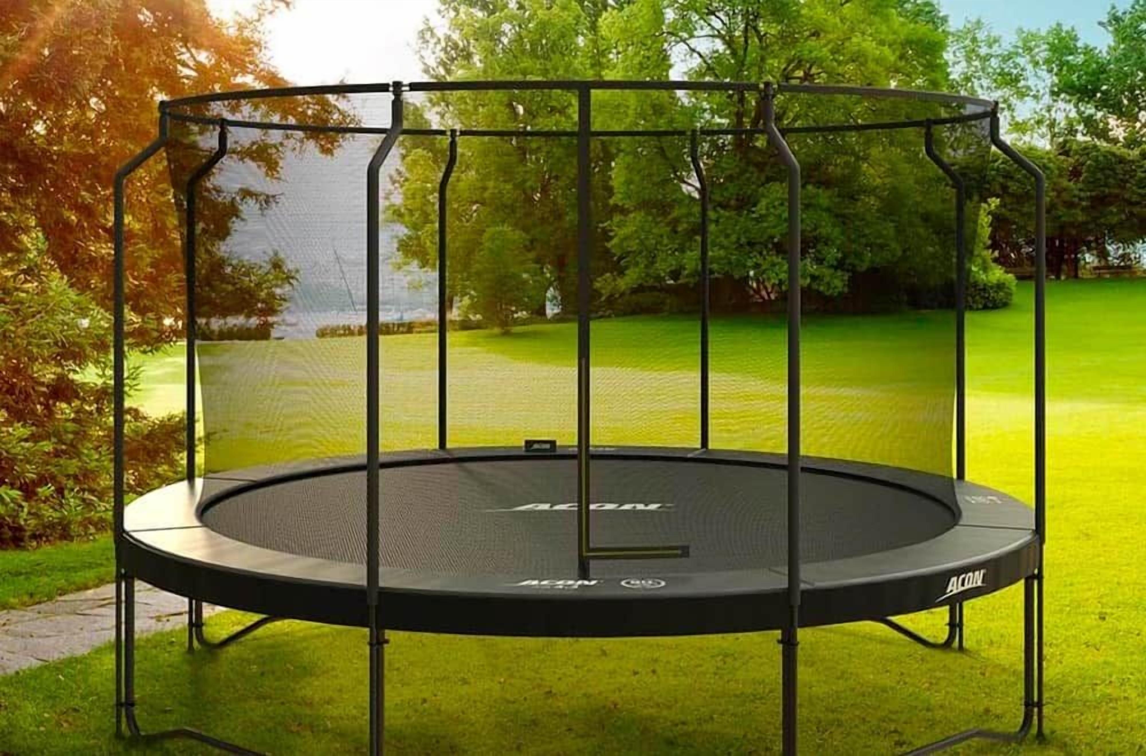 A trampoline with a safety net enclosure, surrounded by a grassy area and trees.