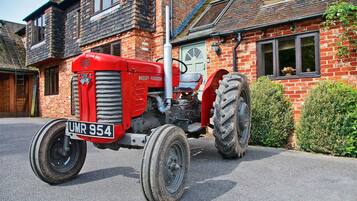 A red Massey-Ferguson tractor parked in front of a brick house with a visible license plate.