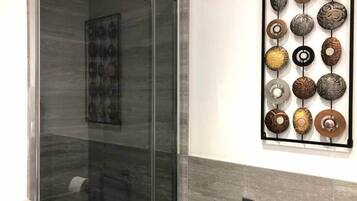 Une salle de bain dotée d’une douche à parois de verre et d’une œuvre d’art murale composée d’objets circulaires.
