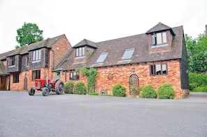 A brick building with multiple windows and a red tractor parked in front.