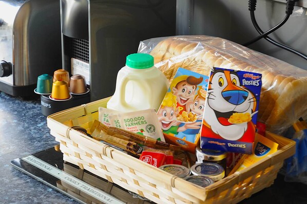 A basket containing a milk carton, a box of Frosties cereal, a bottle of milk, and a loaf of bread.