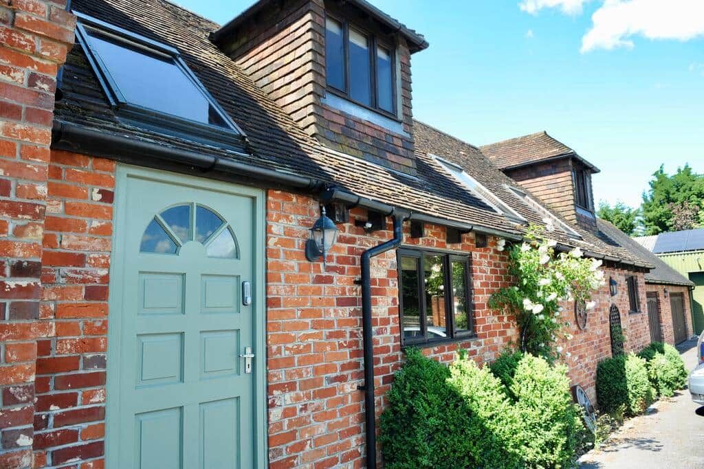 A brick house with a green door, a skylight, and a small window.