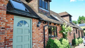 A brick house with a green door, a skylight, and a small window.