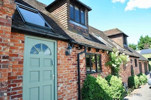 A brick house with a green door, a skylight, and a small window.
