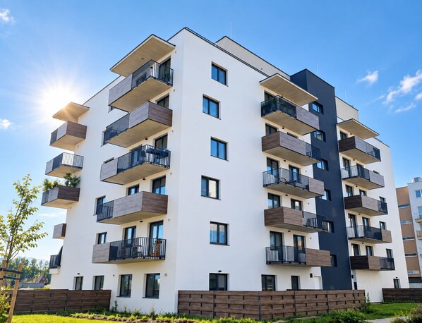 A multi-story residential building with balconies, a flat roof, and a clear sky.