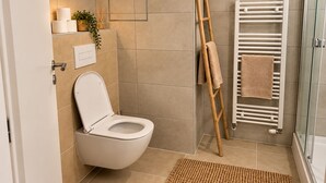 Et badeværelse med toilet, håndklædestang og bruseområde.