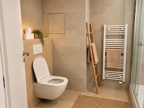 Ein Badezimmer mit Toilette, Handtuchhalter und Duschbereich.