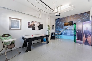 A room with a pool table, a high chair, and a wall with framed pictures and a large screen. - 4BR Themed Home Championsgate Pool & spa (Davenport)