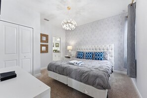 A bedroom with a large bed, a bedside table, a lamp, and a chandelier. - 4BR Themed Home Championsgate Pool & spa (Davenport)