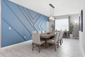 A dining area with a blue accent wall, a wooden table, and six chairs. - 4BR Themed Home Championsgate Pool & spa (Davenport)