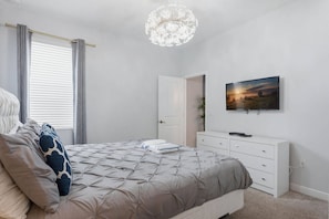 A bedroom with a bed, a dresser, a television, and a chandelier. - 4BR Themed Home Championsgate Pool & spa (Davenport)