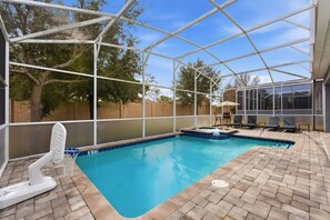 A swimming pool with a hot tub, surrounded by a covered patio area with chairs and a table. - 4BR Themed Home Championsgate Pool & spa (Davenport)