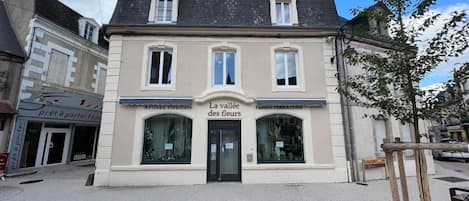 A two-story building with a sign reading 'La vallée des fleurs' and 'Artisan fleuret.'