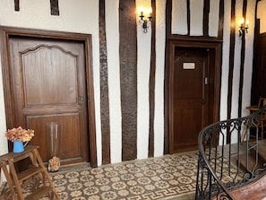 A hallway with two wooden doors, a staircase, and a patterned floor. - Charming apartment in the heart of the Morvan (Luzy)