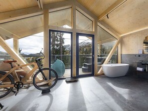 A modern interior with a large bathtub, a bicycle, and a view of the outdoors. - Cabin in Turrach With Sauna and Balcony (Stadl-Predlitz)
