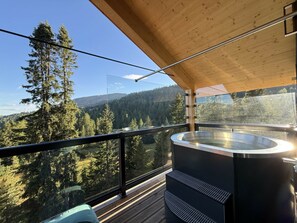 A balcony with a hot tub, wooden deck, and a view of a forested mountain range. - Cabin in Turrach With Sauna and Balcony (Stadl-Predlitz)