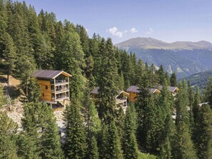 A mountain lodge with multiple wooden cabins surrounded by dense forest, offering panoramic views of the mountains. - Cabin in Turrach With Sauna and Balcony (Stadl-Predlitz)