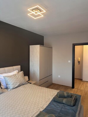 A bedroom with a bed, a wardrobe, a bedside table, and a bathroom door. - Cashmere Suite - Stylish Seaside Stay in Pomorie (Pomorie)