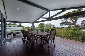 Ein überdachter Außenbereich mit Holztisch und -stühlen sowie einem Metalldach und Blick auf die umliegende Landschaft.