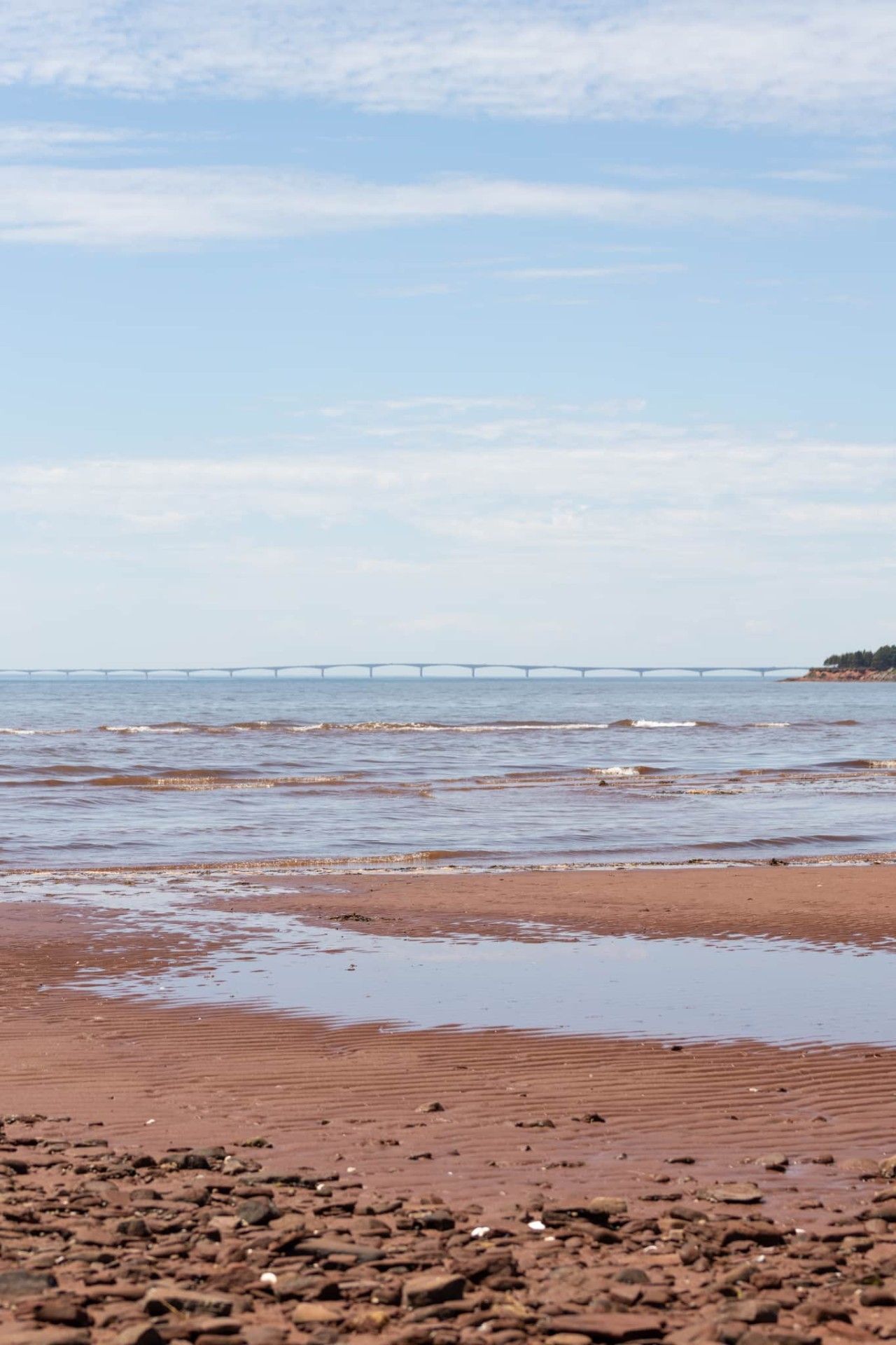 A beach with a bridge in the distance.