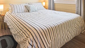 Ein Schlafzimmer mit einem Bett, einer runden Wanduhr, einem Fenster mit Vorhängen und einem Deckenventilator.