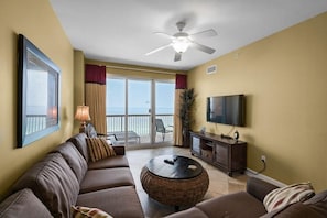 Ein Wohnzimmer mit einer Couch, einem runden Couchtisch, einem Fernseher und einem Deckenventilator.