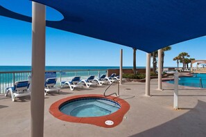 Ein Poolbereich mit Liegestühlen, einem Whirlpool und Blick auf den Ozean.