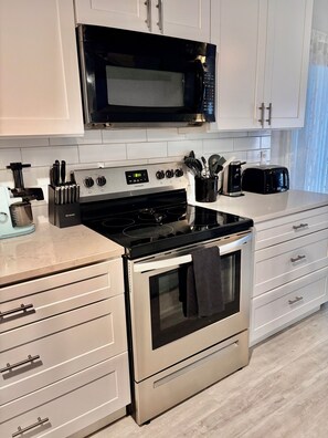 Una cucina con piano cottura in acciaio inossidabile, forno a microonde e mobili bianchi.