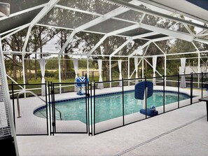 An indoor swimming pool with a glass enclosure, a diving board, and a lifeguard chair. - Spacious Pet Friendly 4-bedroom home in Port St. Lucie with pool & fenced yard (Port St. Lucie)