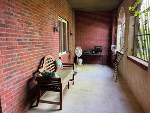 A brick-walled outdoor area with a wooden bench, a fan, and a grill station. - Peaceful Country Atmosphere with City Convenience. (Owens Cross Roads)