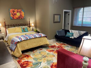 A bedroom with a bed, a nightstand, a dresser, a window with blinds, and a floral-patterned rug. - Peaceful Country Atmosphere with City Convenience. (Owens Cross Roads)