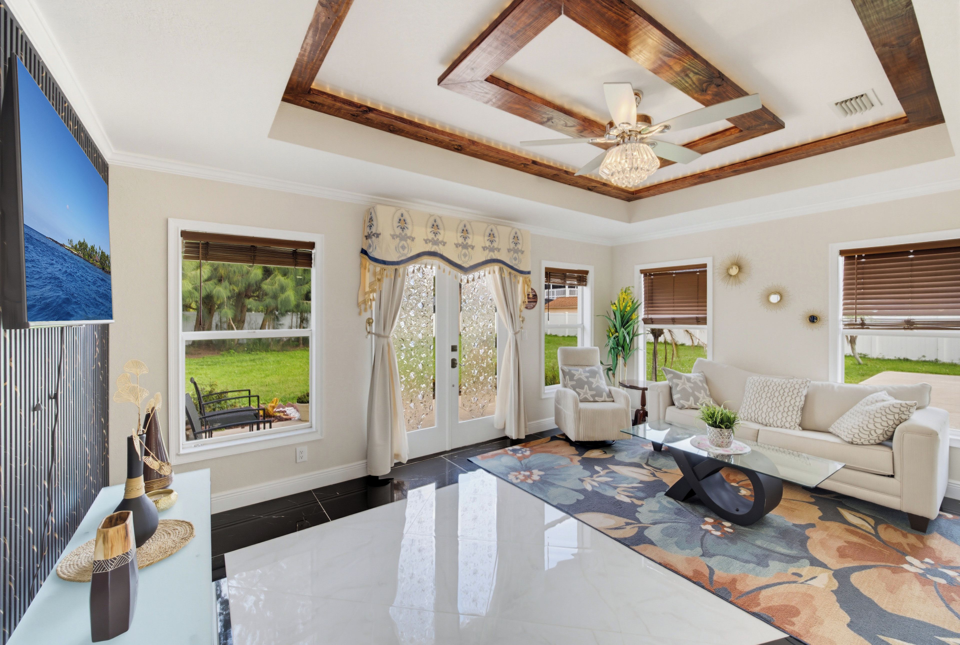 A spacious living room with a large window, a ceiling fan, and a modern fireplace.