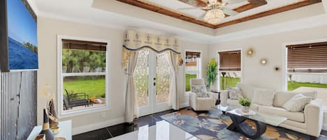 A spacious living room with a large window, a ceiling fan, and a modern fireplace.