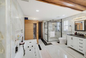 Ein modernes Badezimmer mit einer Duschkabine aus Glas, einer Badewanne, einer Toilette und einem Waschtisch mit Spiegel.