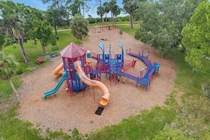 Ein Spielplatz mit Rutsche, Klettergerüsten und einem überdachten Spielbereich.