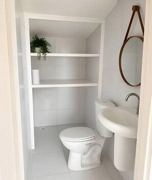 A small, white bathroom with a toilet, sink, and shelves. - Olinda sitio histórico - Loctemp (Olinda)