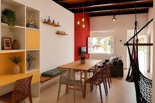A dining area with a wooden table and chairs, a red accent wall, and a hanging chair. - Olinda sitio histórico - Loctemp (Olinda)
