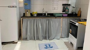 Cozinha compacta com geladeira, fogão e micro-ondas.