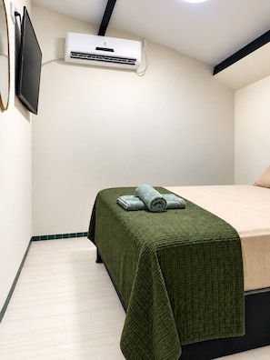 A hotel room with a bed, a flat-screen TV mounted on the wall, and an air conditioning unit. - Olinda sitio histórico - Loctemp (Olinda)